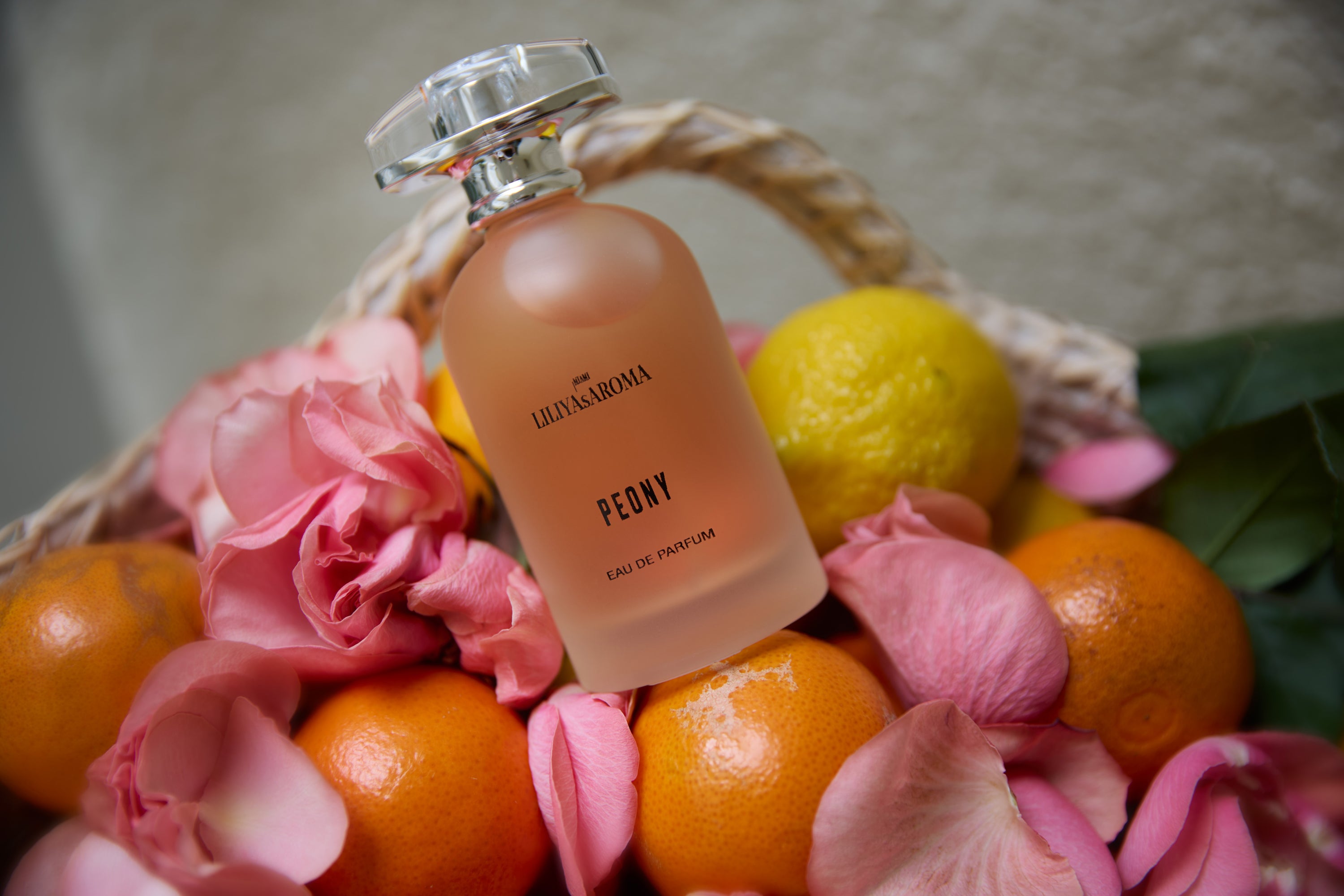 Peony Eau De Parfum by Liliya’s Aroma in a luxury frosted glass bottle surrounded by fresh citrus fruits and pink peony petals, elegant floral perfume for women